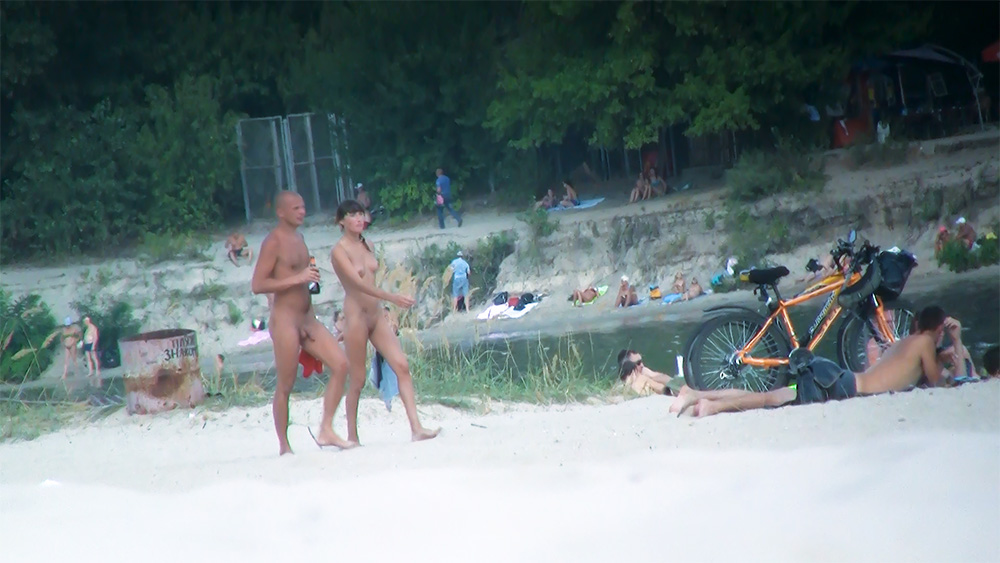 Nudist Couple Strolling Across the Sandy Shore