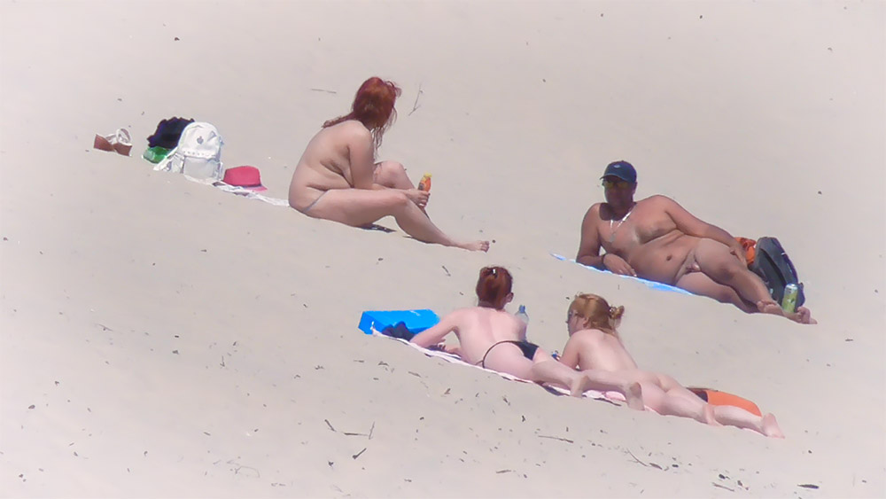 Four Naturists Resting on Towels at the Beach