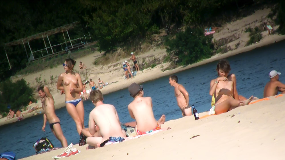 Zes toplessbaders langs een zandige rivieroever