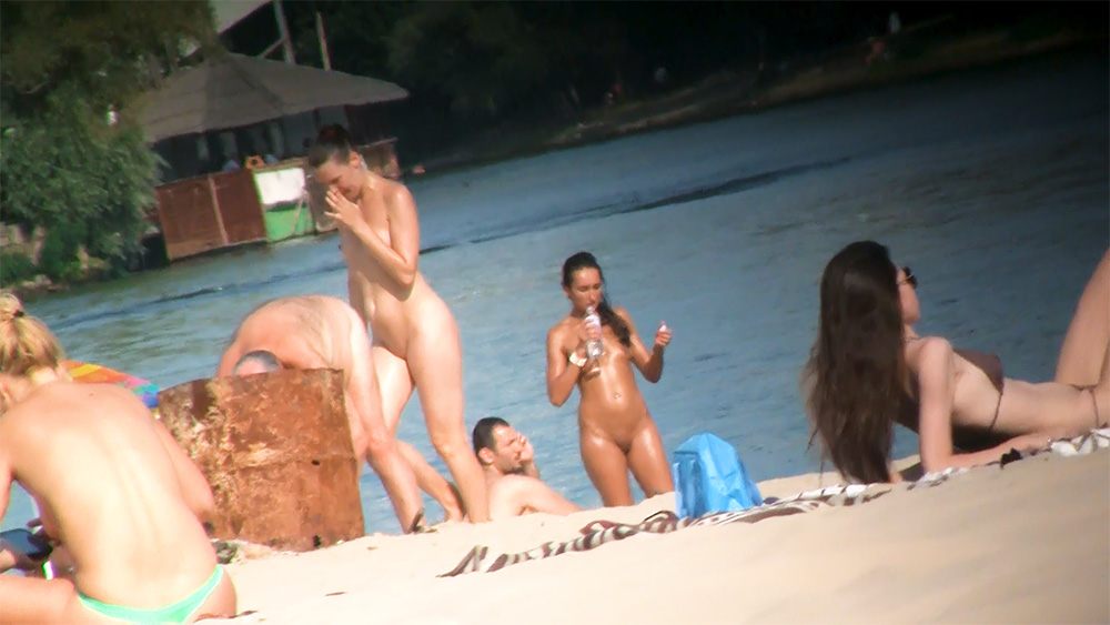 Four Nudists Standing Together on a Sandy Beach