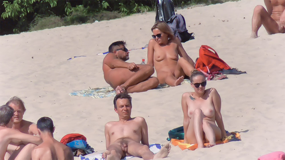 Four Nudists Sitting on Towels at a Sandy Beach