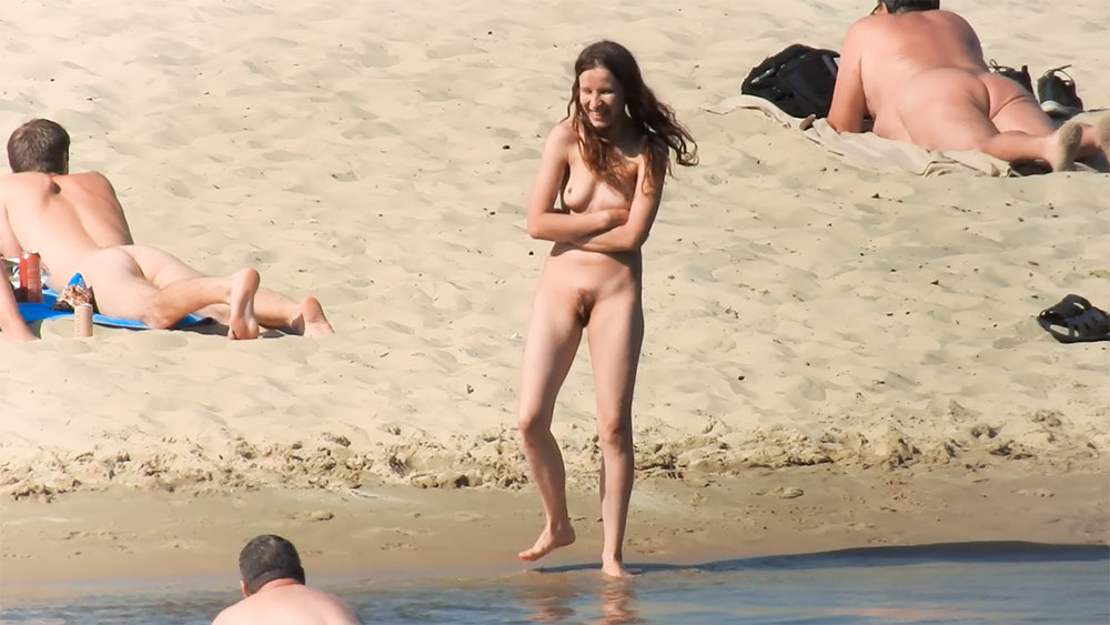 Moment op het natte zand met een naaktstrandbaadster