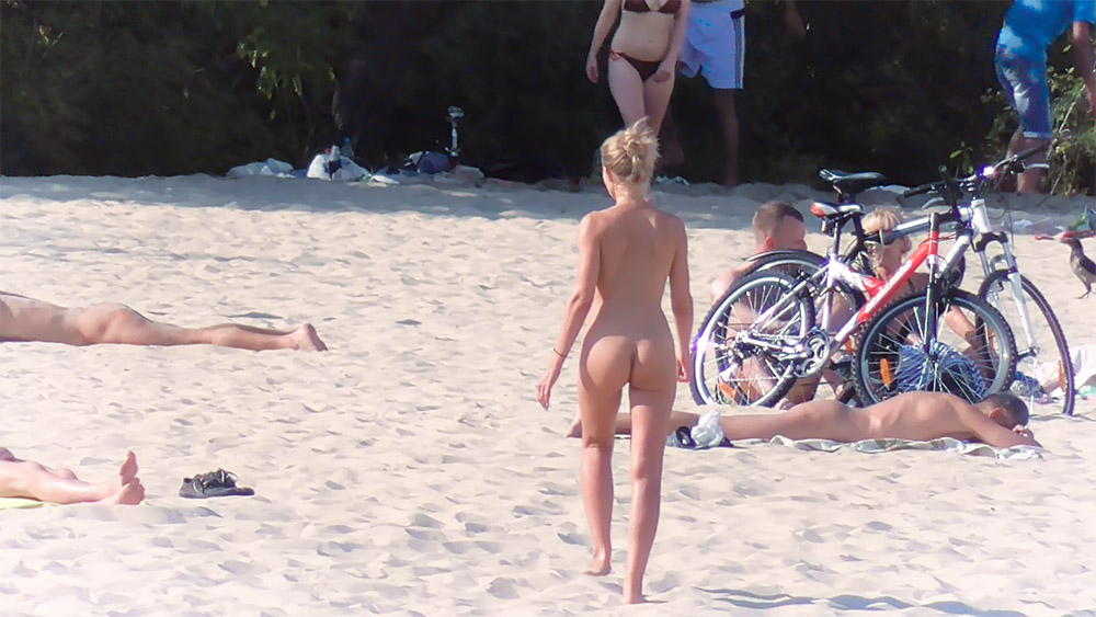 Nude Beach with Parked Bicycles and a Walking Sunbather