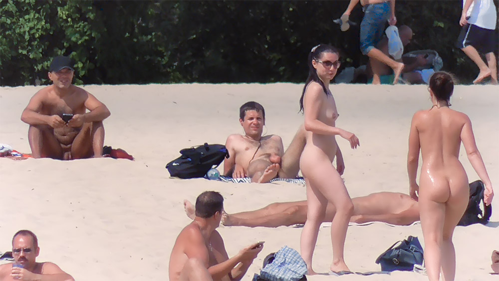 Standing and Lounging Nudists on a Bright Sandy Beach