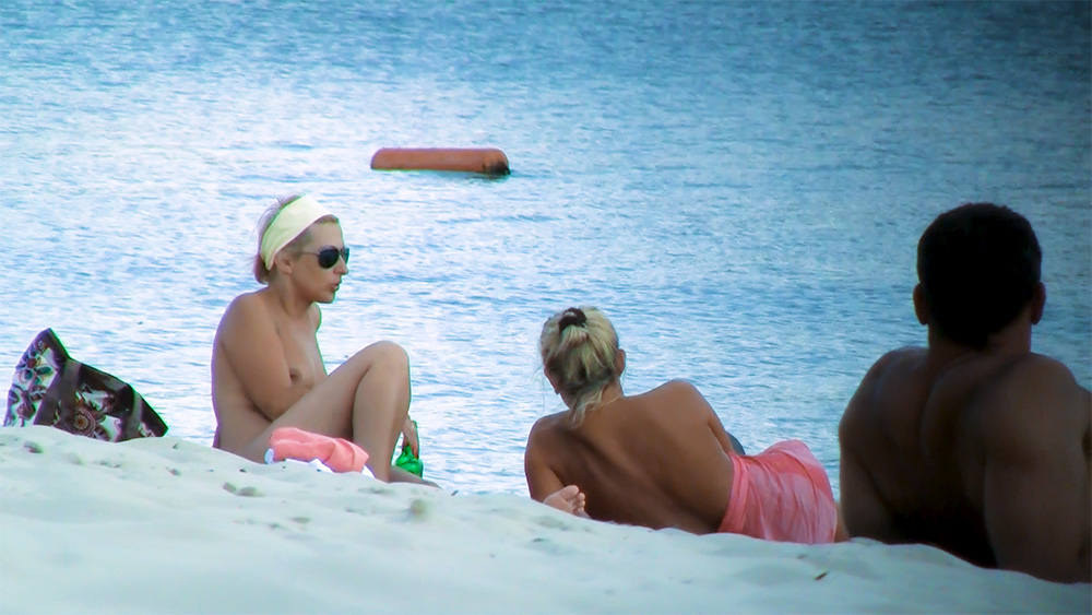 Two Nudists Resting Side by Side on Warm Sand