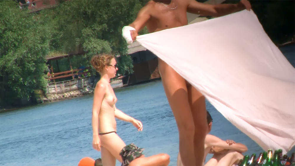 In piedi sulla riva di una spiaggia in topless, con pantaloncini mimetici