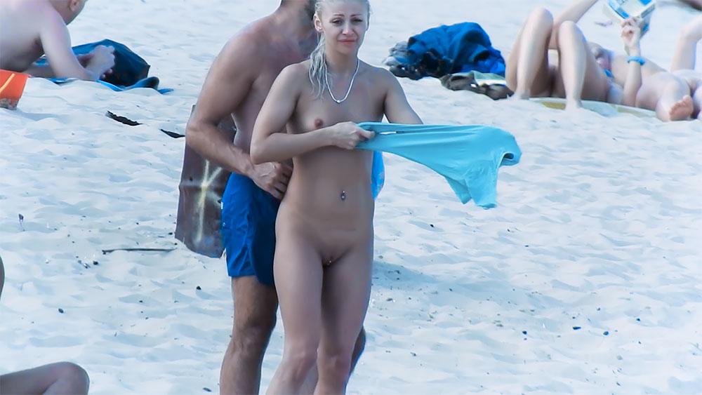 Okamžik na písečné nudistické pláži s modrou látkou