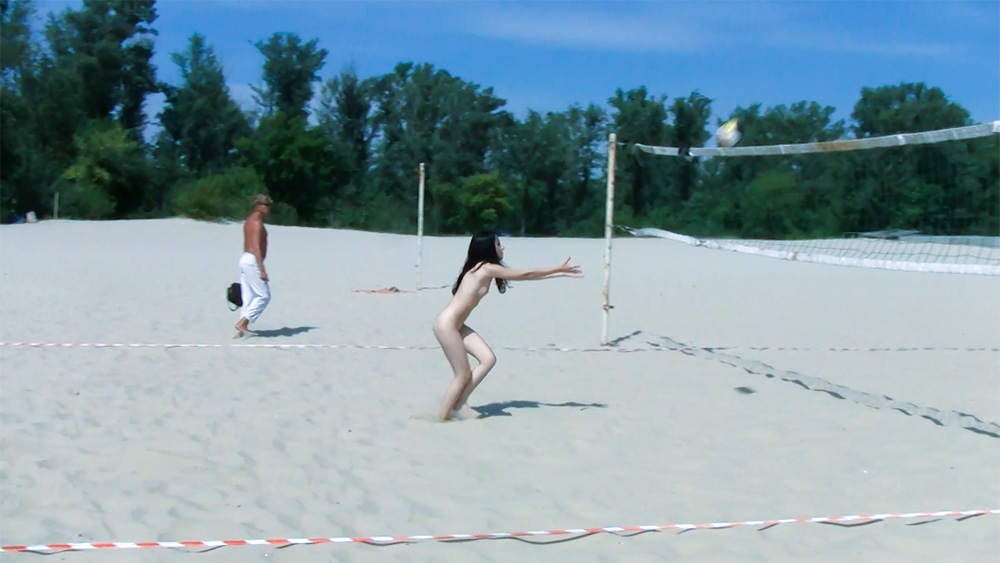 Volejbalová síť na písečné pláži s nudistickou hráčkou