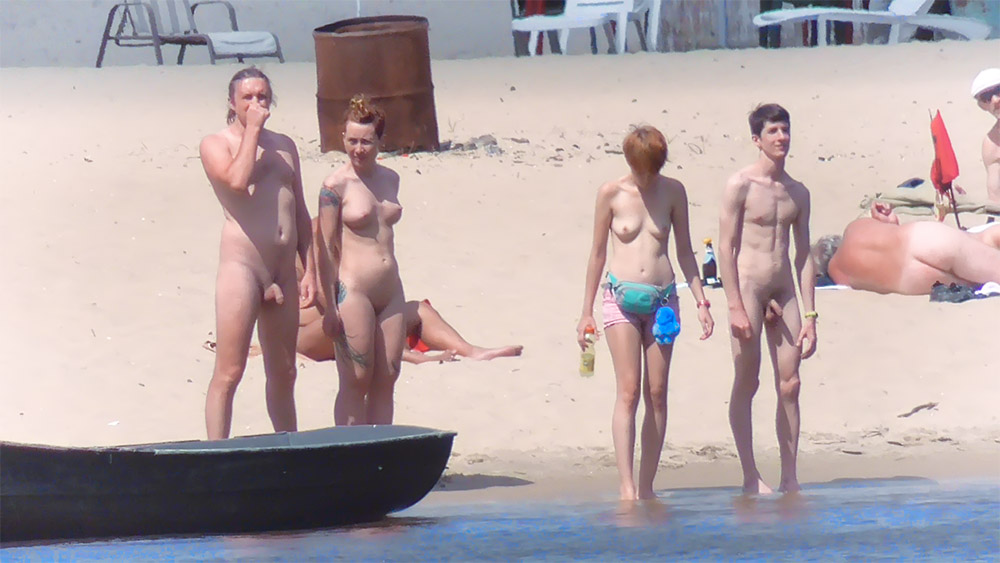 Four Naturists Gathered at the Water's Edge on Sand