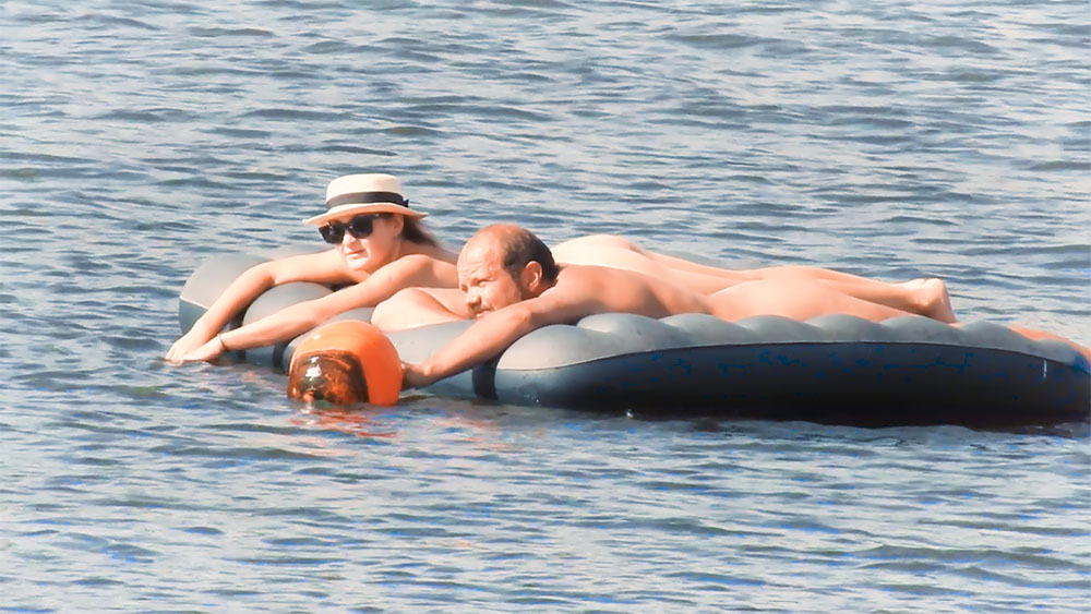 Two Naturists Drifting on Air Mattresses Offshore