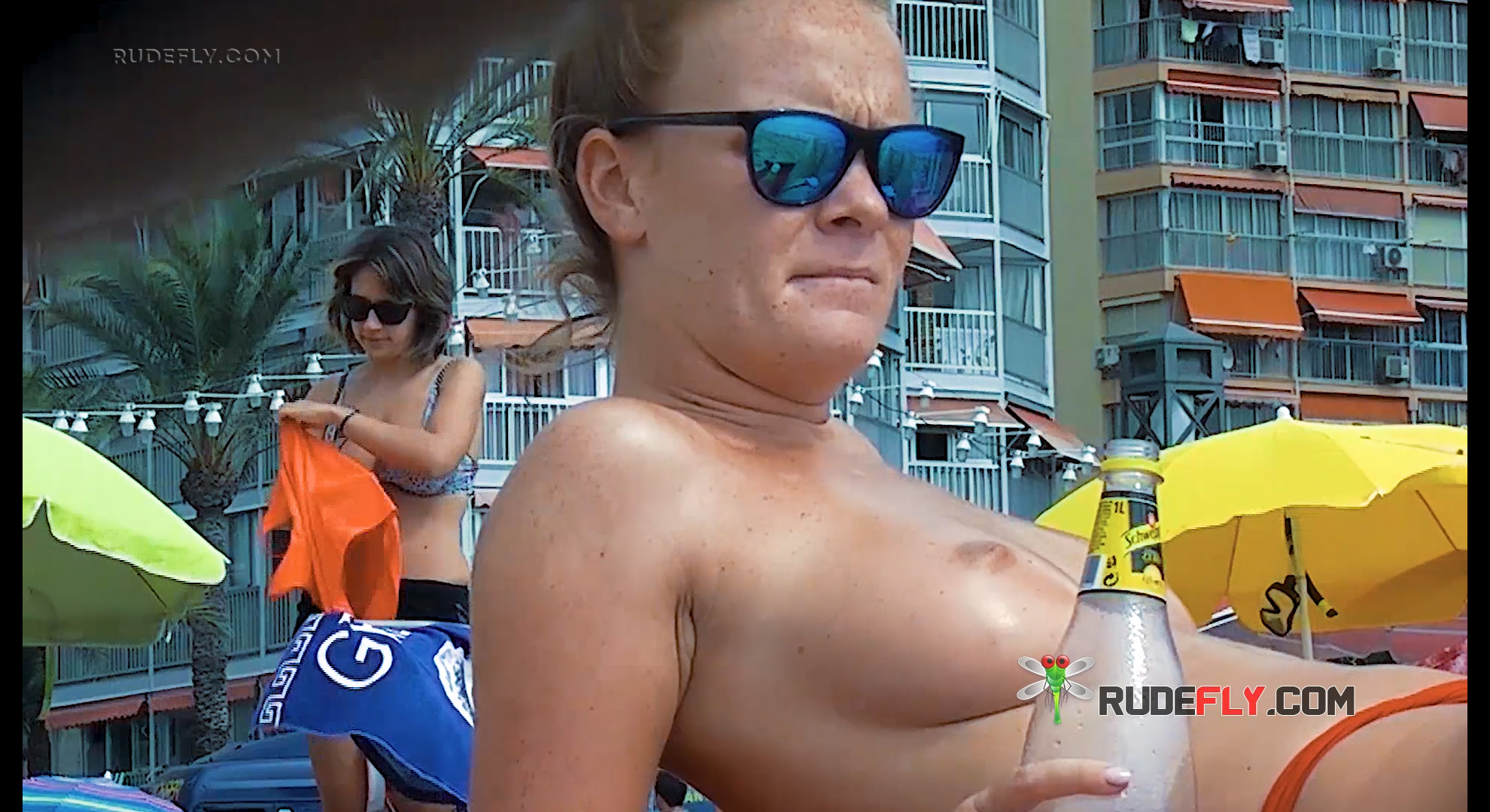Two Topless Sunbathers in an Urban Beach Setting