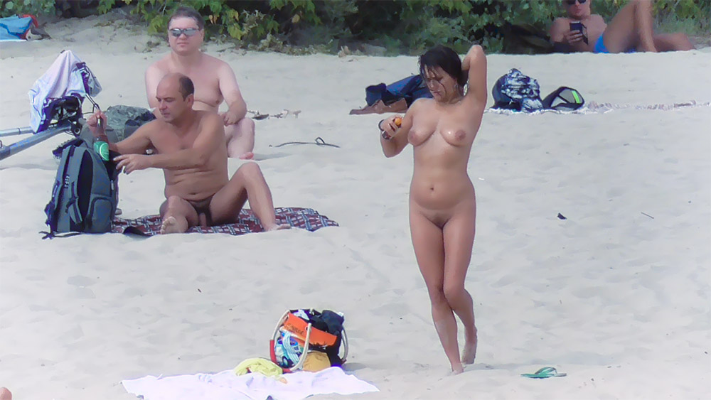 Vrouw poseert op een naaktstrand bij een oranje tas