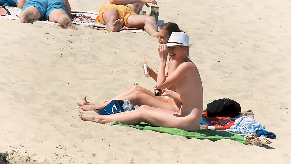 Applying Sunscreen Topless on a Sandy Beach Towel