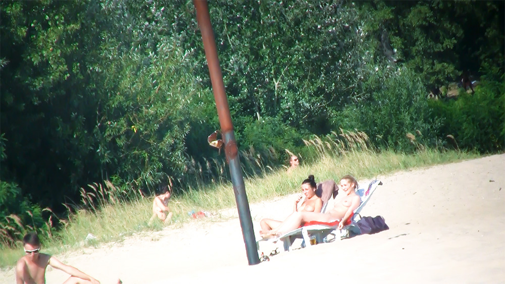 Two Women Topless on Side-by-Side Beach Chairs