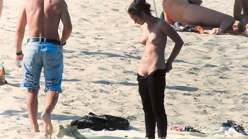 Upravování tmavých kalhot na topless pláži
