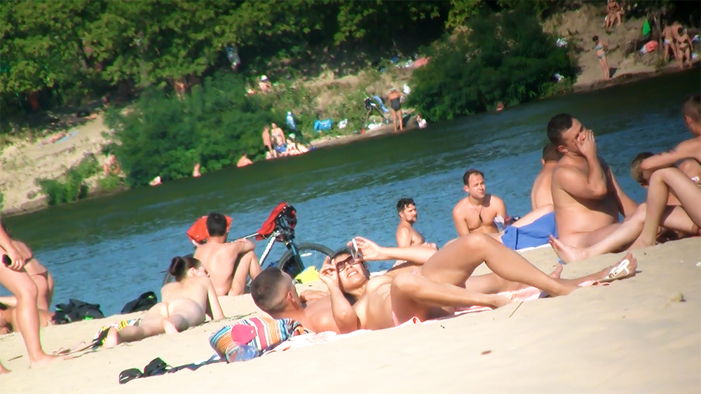 Four Nudists Resting on Towels at a Sandy Nude Beach