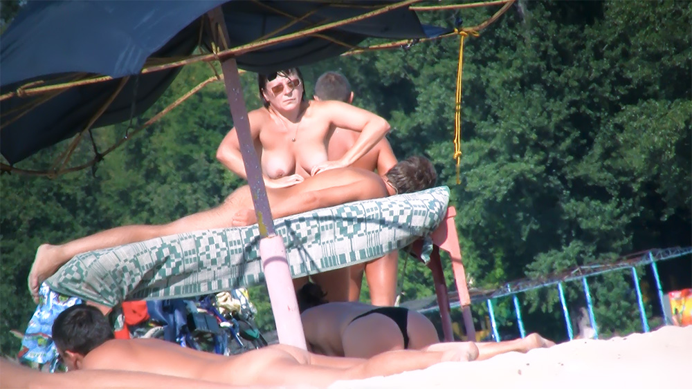 Three Nudists on a Shaded Platform with Patterned Cloth