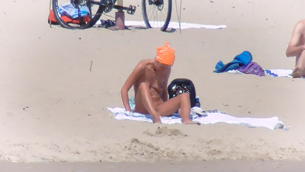 Two Nudists Sharing a Towel on Warm Sand
