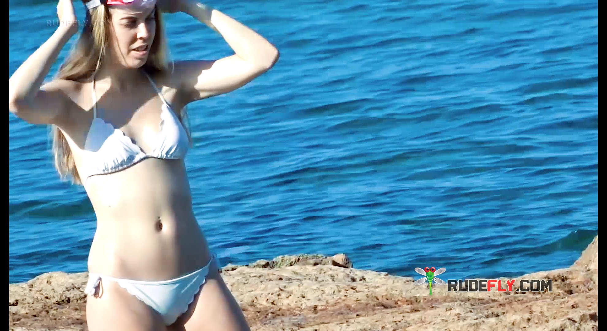 Adjusting Hair on Rocky Shore in White Bikini at Topless Beach