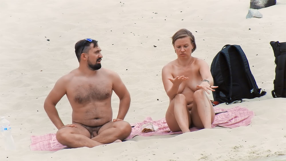 Žena si prohlíží ruku na nudapláži