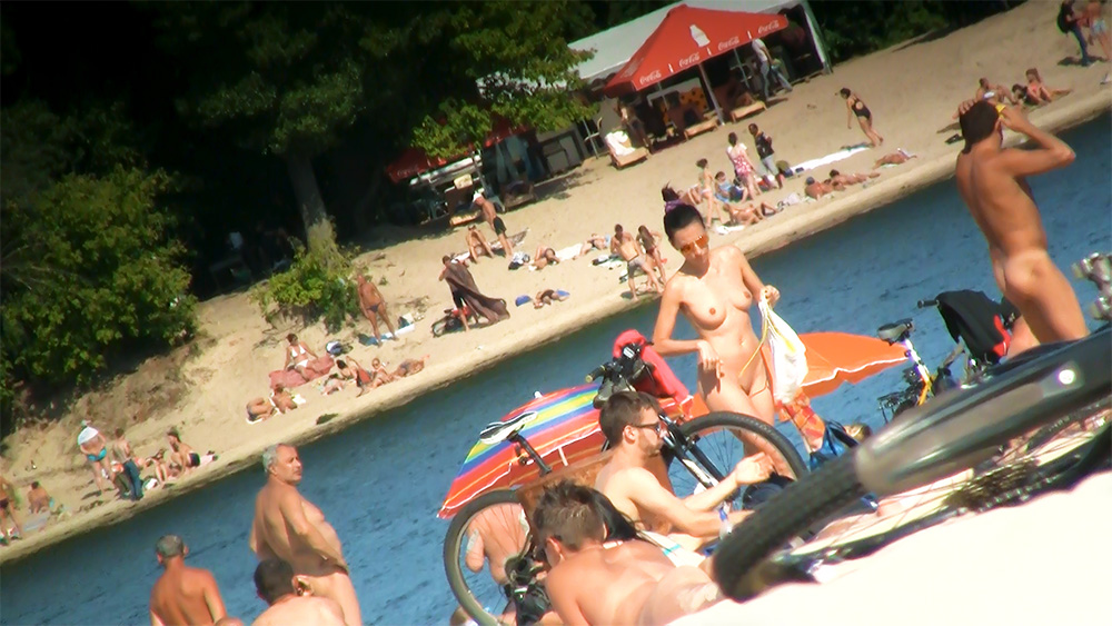 Crowded Nude Beach with Bicycle and Striped Umbrella
