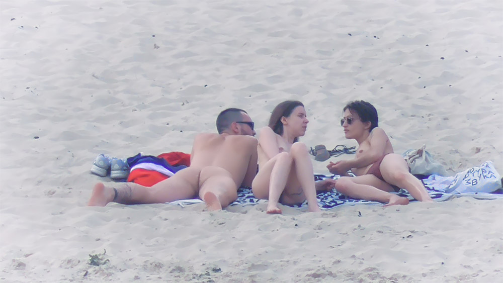 Tre naturisti condividono i teli sulla sabbia