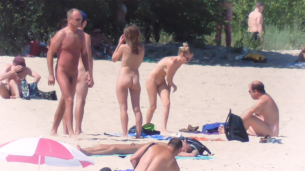 Vijf naturisten verzameld bij handdoeken op een naaktstrand