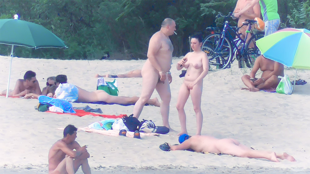 Four Nude Beach Visitors Gathered Near Parked Bicycles