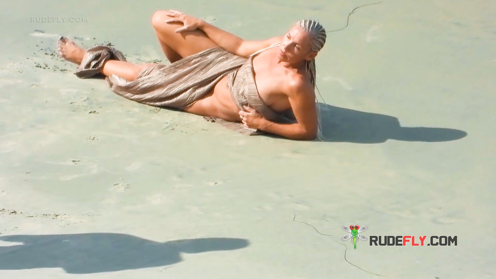 Recostada sobre la arena mojada en la orilla de una playa de topless
