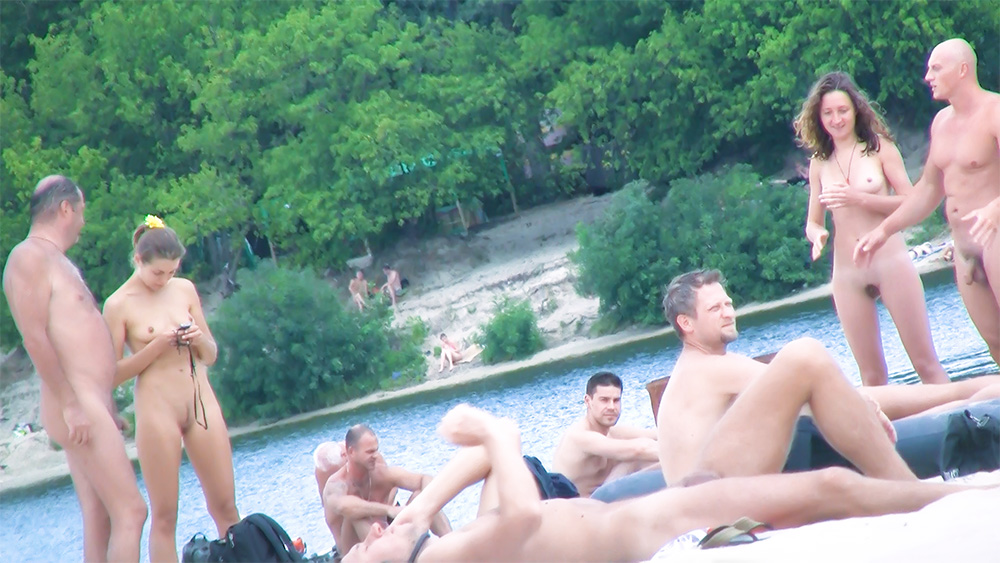 Šest nudistů pohromadě na písečném břehu řeky