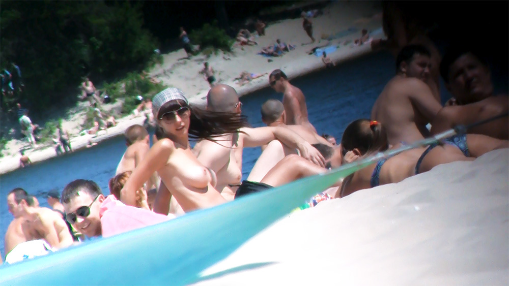 Topless Woman in Cap and Sunglasses Among Beachgoers