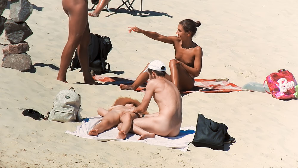 Four Nudists Gathered on Towels at a Nude Beach