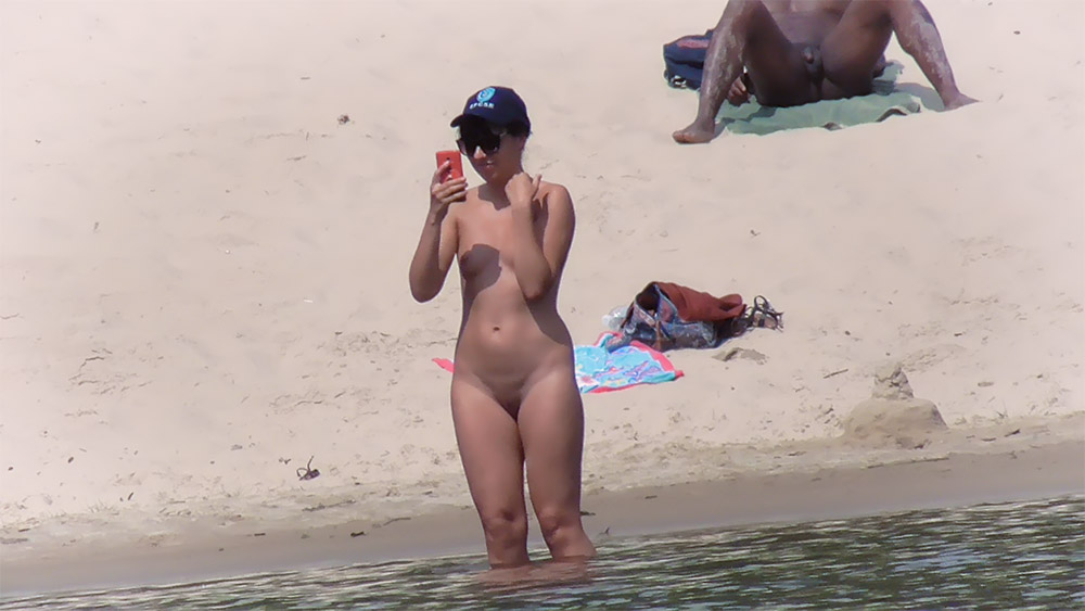 Sandy Shoreline Nudists with a Bather Wading at the Edge