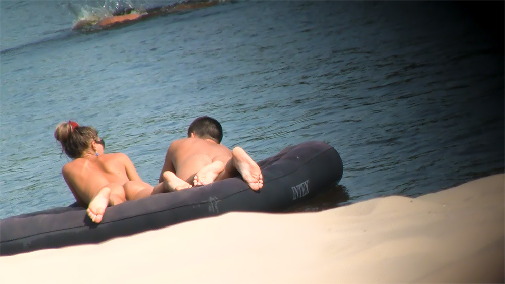 Playful young nudist has fun at the  beach