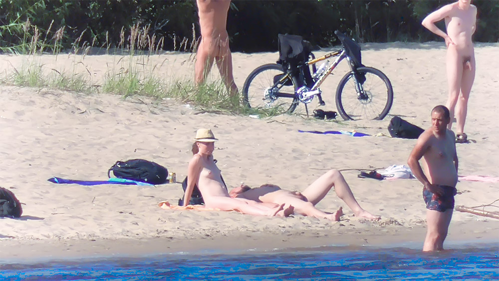 Dos nudistas descansando juntos en una playa nudista de arena