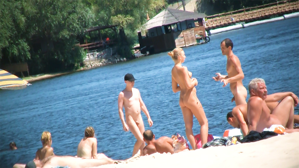 Šest naturistů na sluncem zalité pláži u jezera