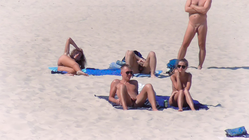 Pět nudistů sedí spolu na plážových ručnících