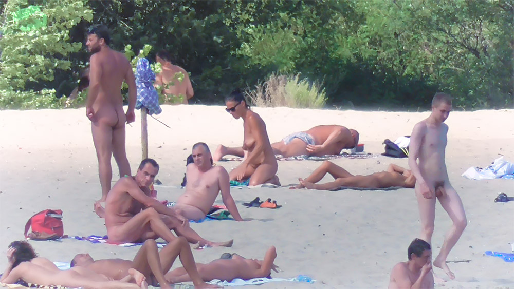 Entspannen im Sand zwischen FKK-Anhängern nahe einem Sonnenschirm