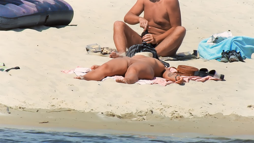 Dva nudisté odpočívají na osuškách u písečných kamenů