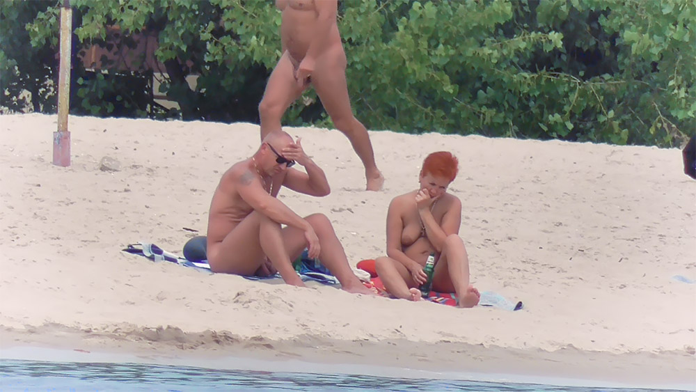 Two Nudists Resting on the Sand with a Bottle