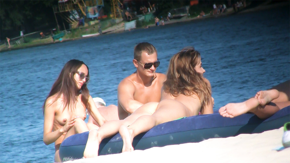 Three Nudists Sharing an Inflatable Raft on the Water