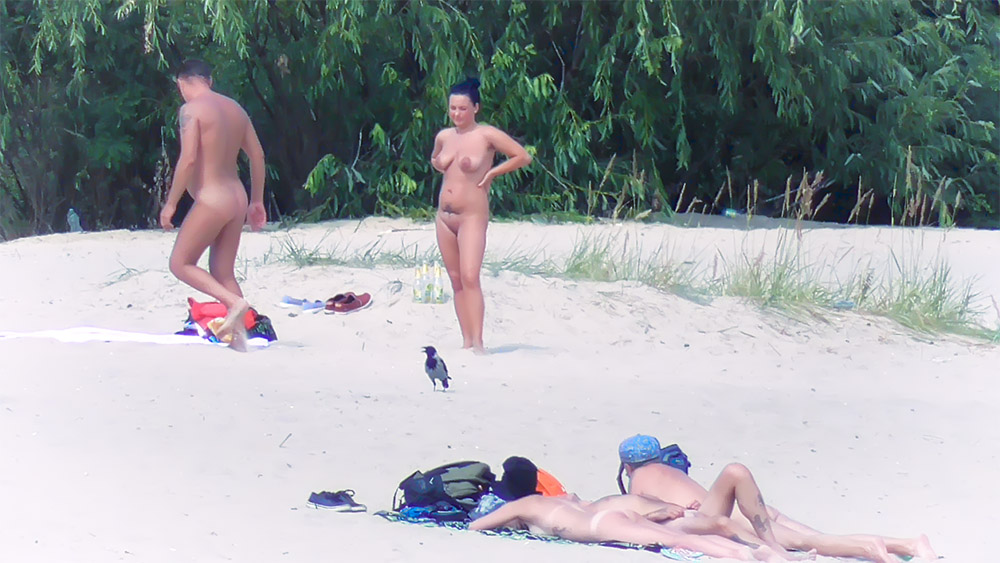 Poza stojąca na plaży dla nudystów obok butelek z wodą