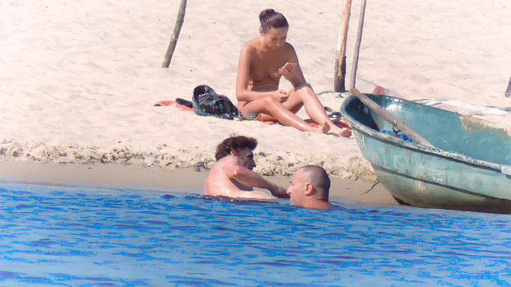 Checking Phone Topless Beside a Moored Wooden Boat