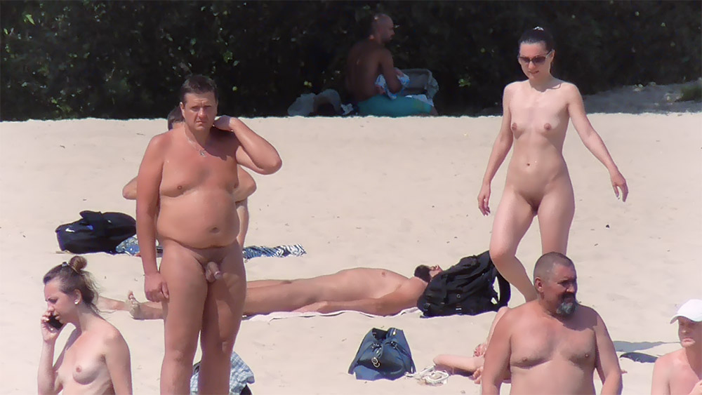 Três Nudistas na Areia com uma Mulher de Pé