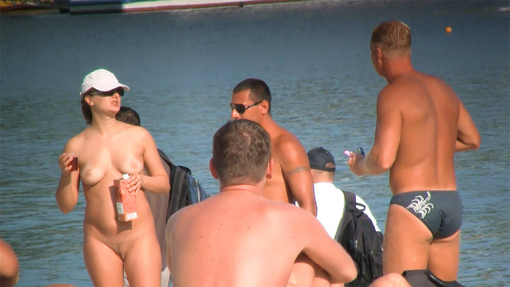 Four Nudists Chatting on a Sunny Shoreline