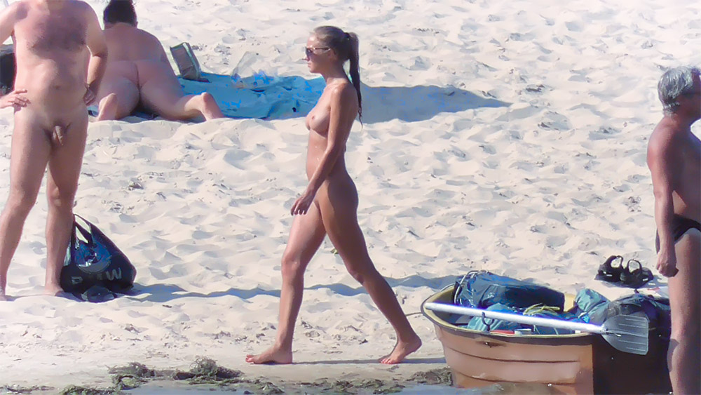 Procházka po nudistické pláži kolem opalující se ženy na modrém ručníku