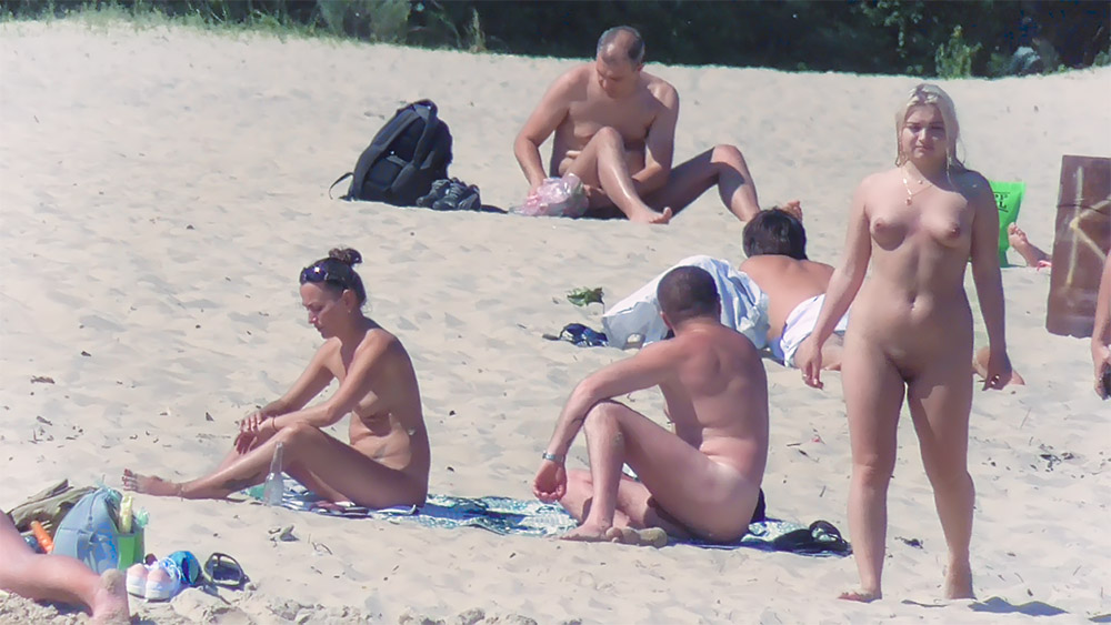 Six Nudists Gathered on Towels Along the Sand