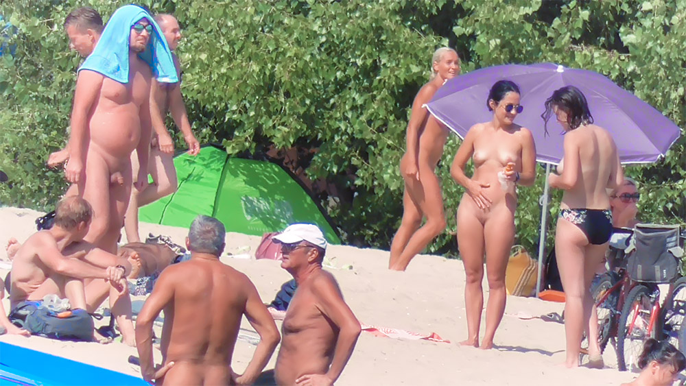 Four Nudists Gathered Beneath a Purple Beach Umbrella