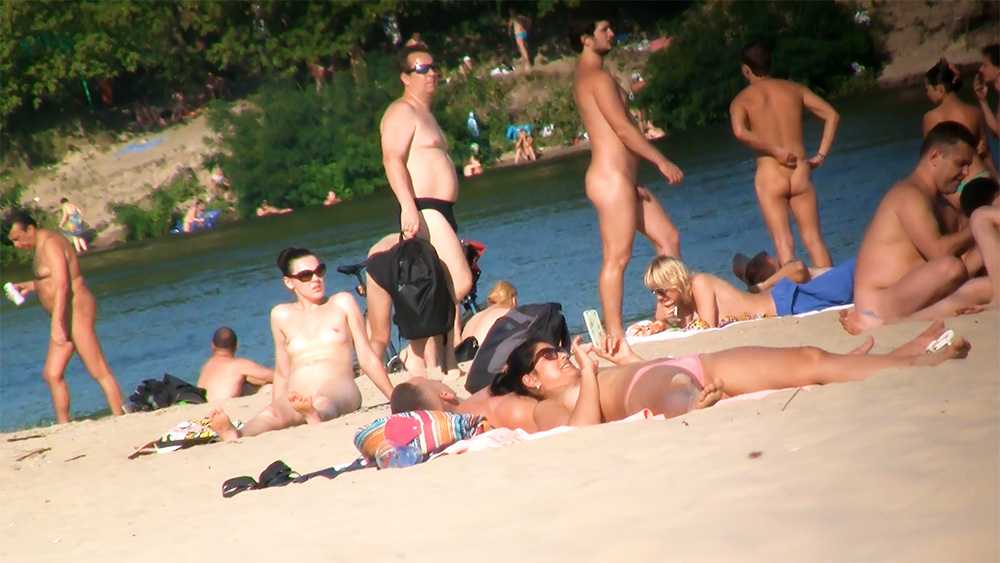 Vijf naturisten bij elkaar op het zand langs de rivier