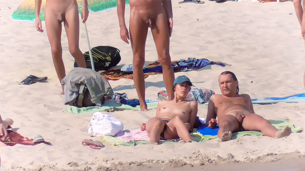 Four Nudists Gathered Around Towels on the Sand